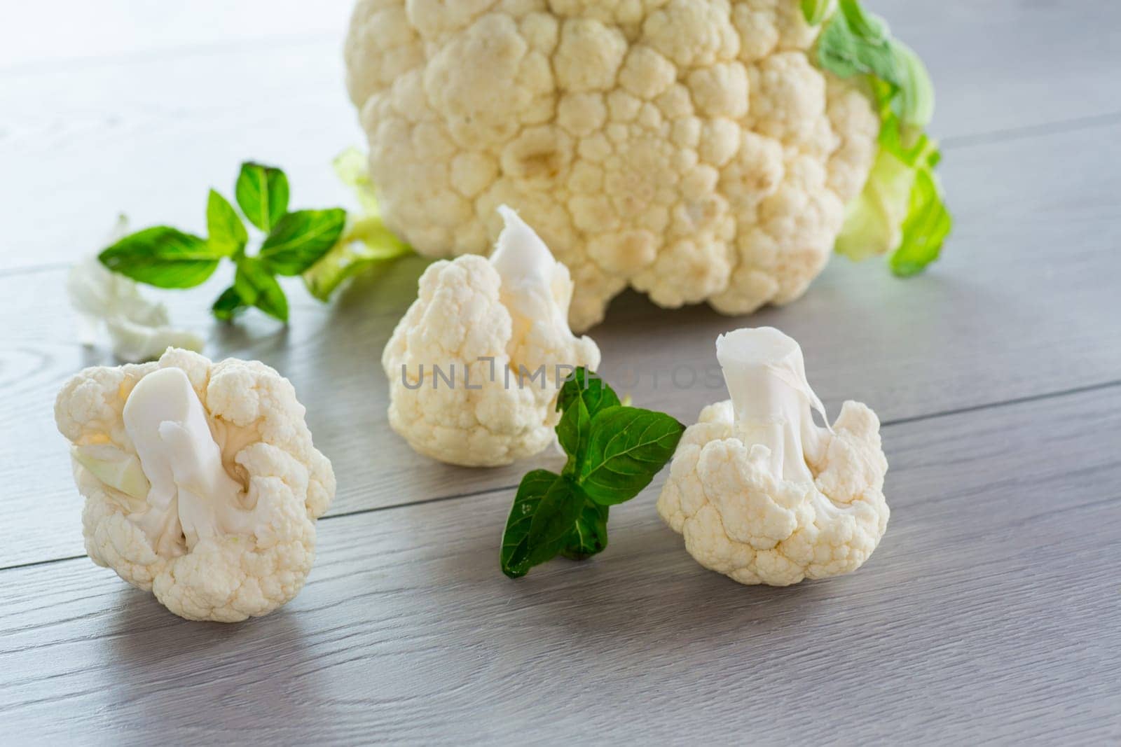 slices of raw small raw cauliflower on wooden table by Rawlik