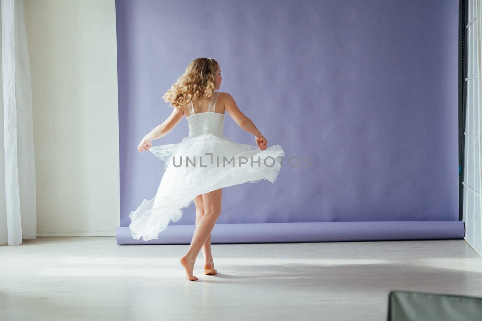 Girl of 10 years in a dress dances to the music alone in the room