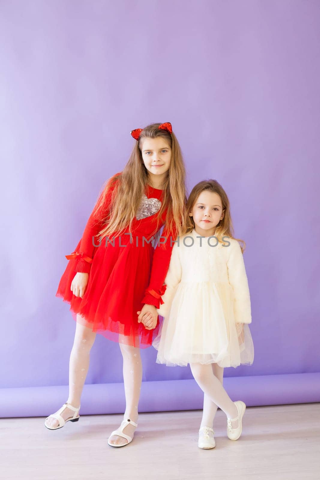 two girl in red and white dresses on a purple background