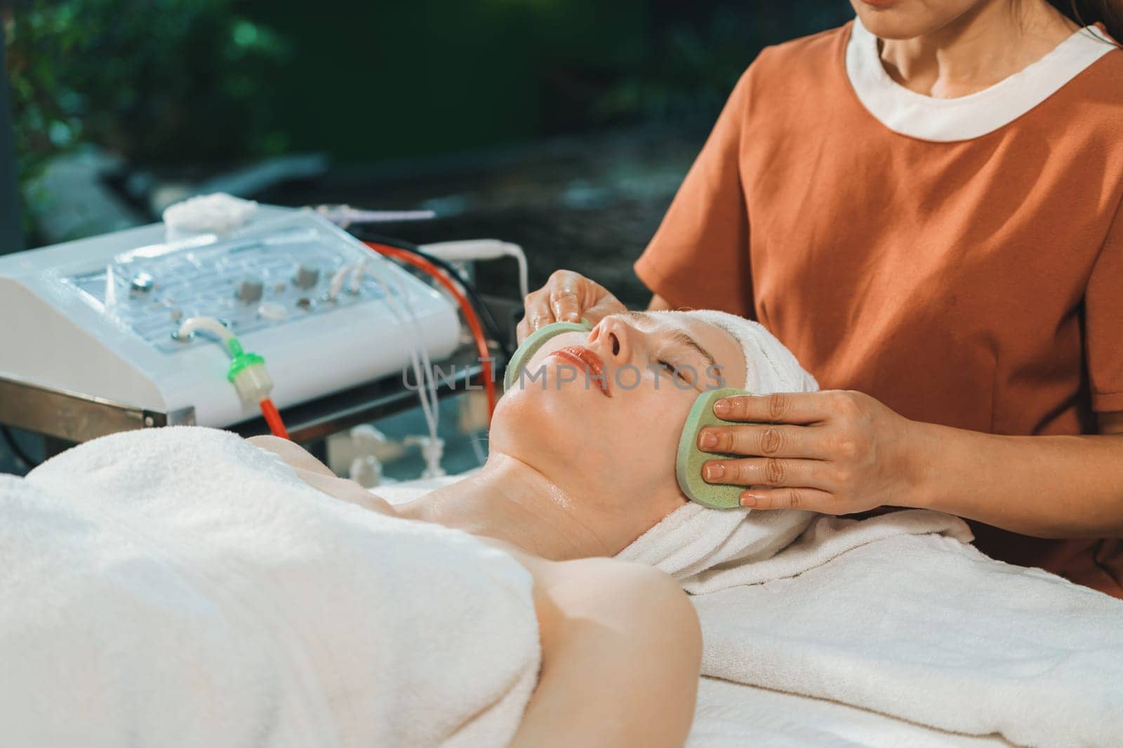 Attractive caucasian woman receive electrical facial treatment. Beautiful girl lies on spa bed while having medical treatment from professional doctor from medical spa center. Tranquility.