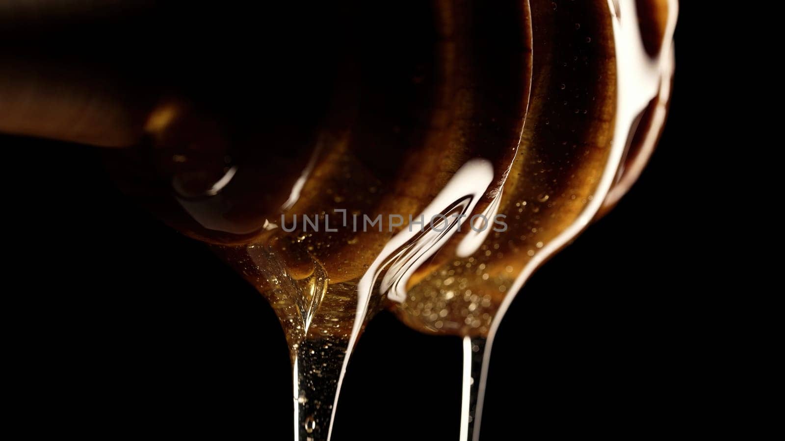 Organic honey flows from olive wood dipper stick spoon, tasty process. Apiary, beekeeping concept. Dripping, pouring sweet fluid nectar in slow motion. High quality