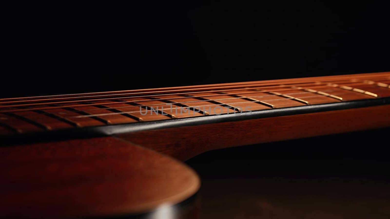 Macro of strings on redwood acoustic guitar fretboard. Classical music, sound background. High quality