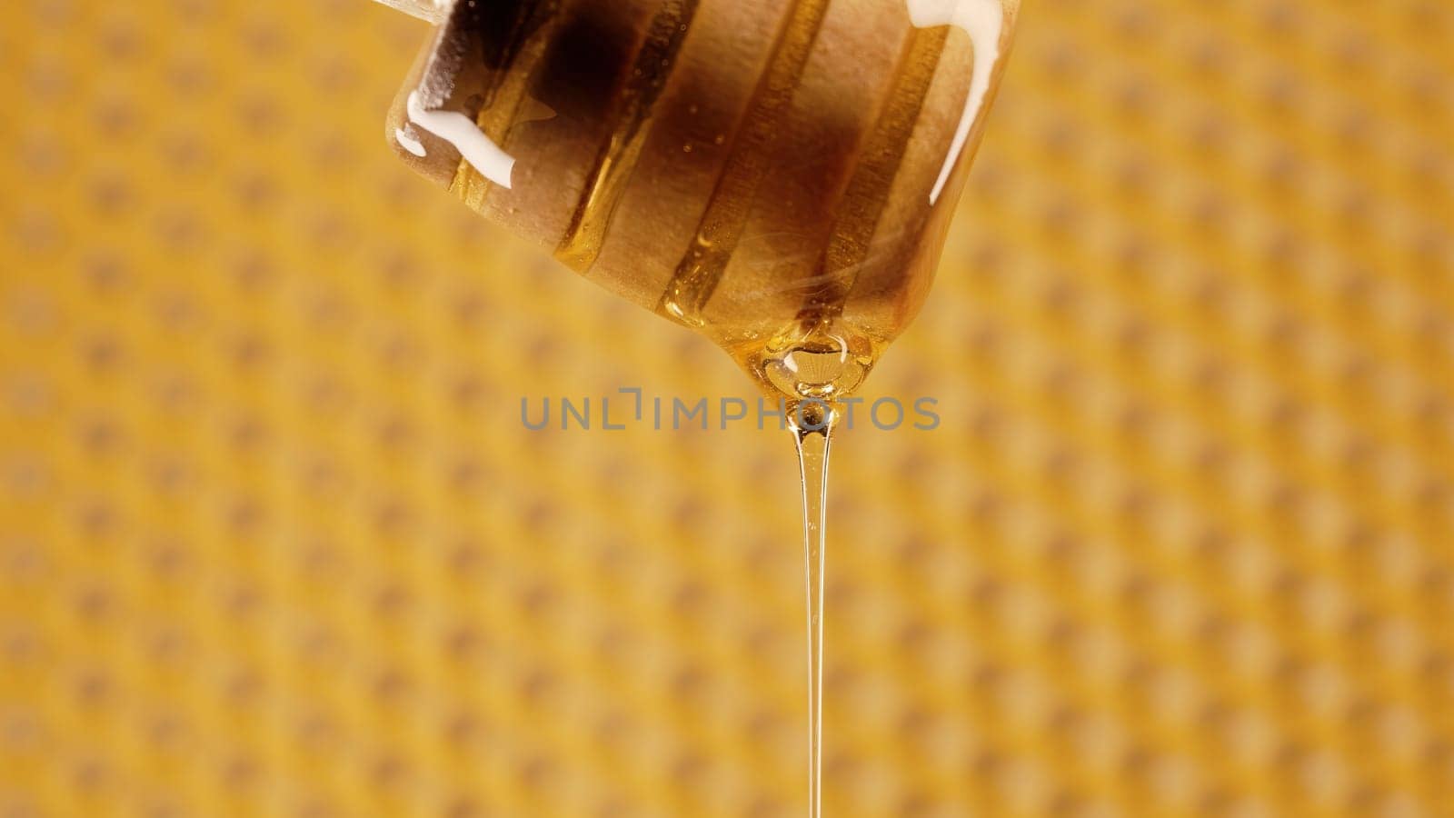 Organic honey flows from olive wood dipper stick spoon, tasty process. Apiary, beekeeping concept. Dripping, pouring sweet fluid nectar in slow motion. High quality