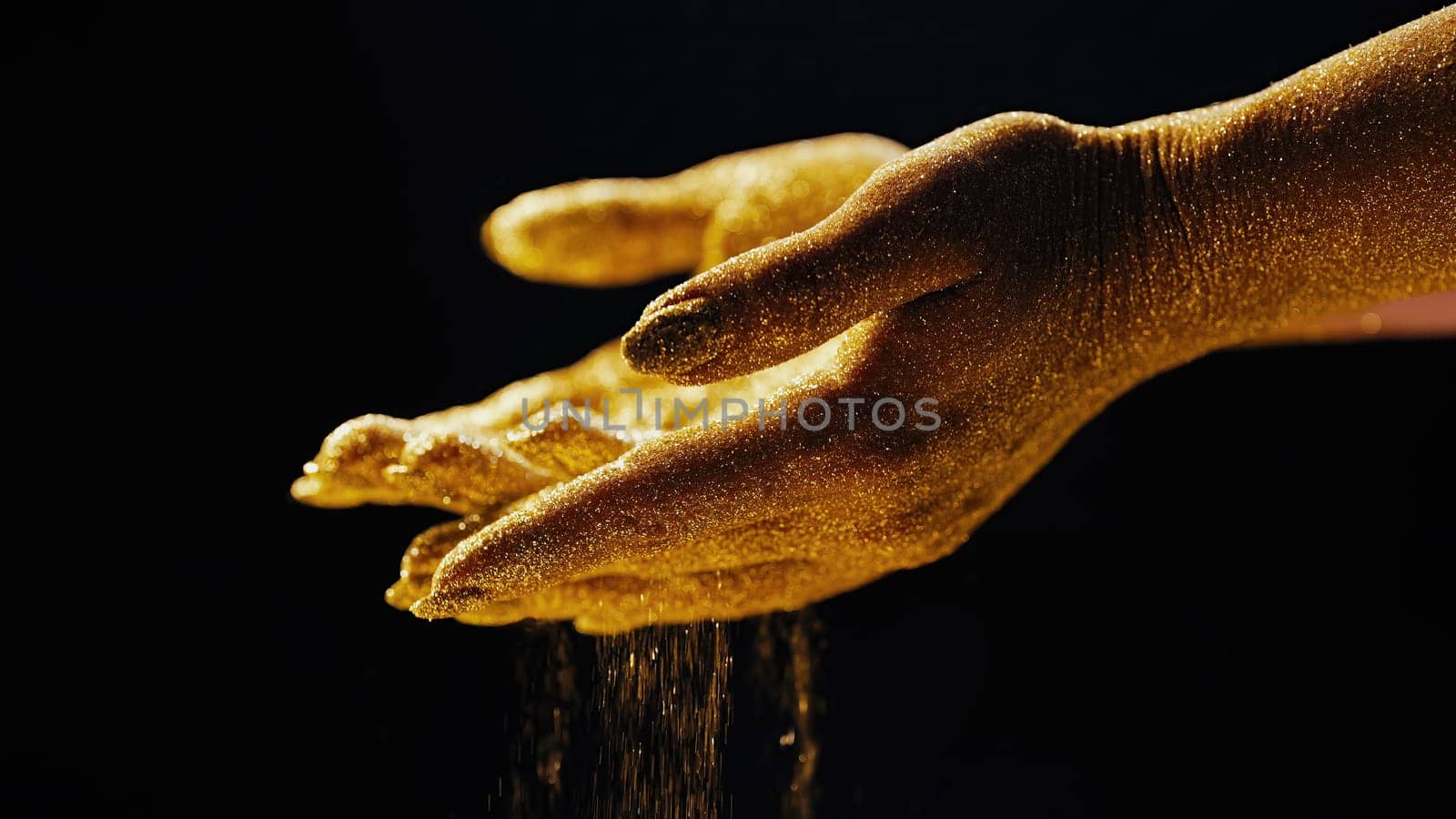 Golden glittering woman hands with dust or sand on black background. Shimmer, time, life moments, deadline, business management, educational creative content concept.