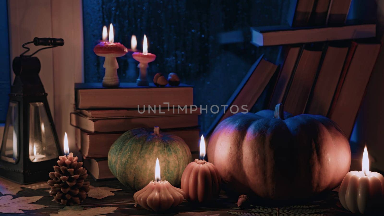 Perfect hygge autumn ambience. Stack of paper books, candles near rainy window. by kristina_kokhanova