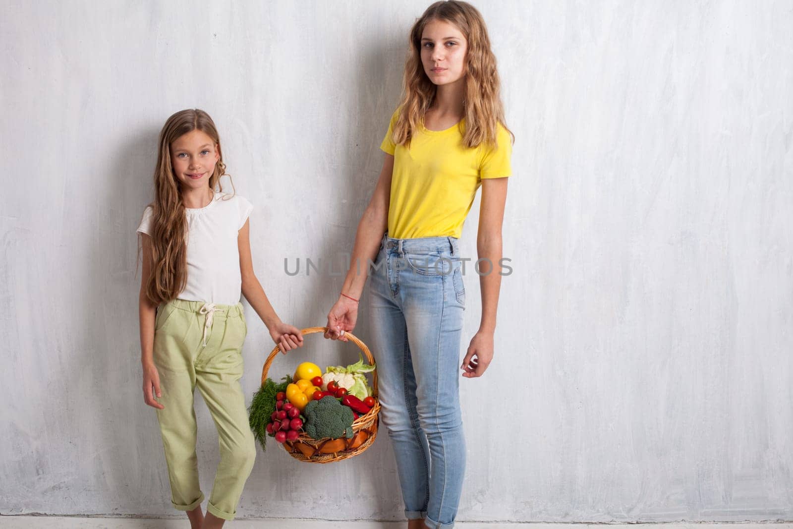 two girls holding a basket of ripe vegetables radish pepper by Simakov