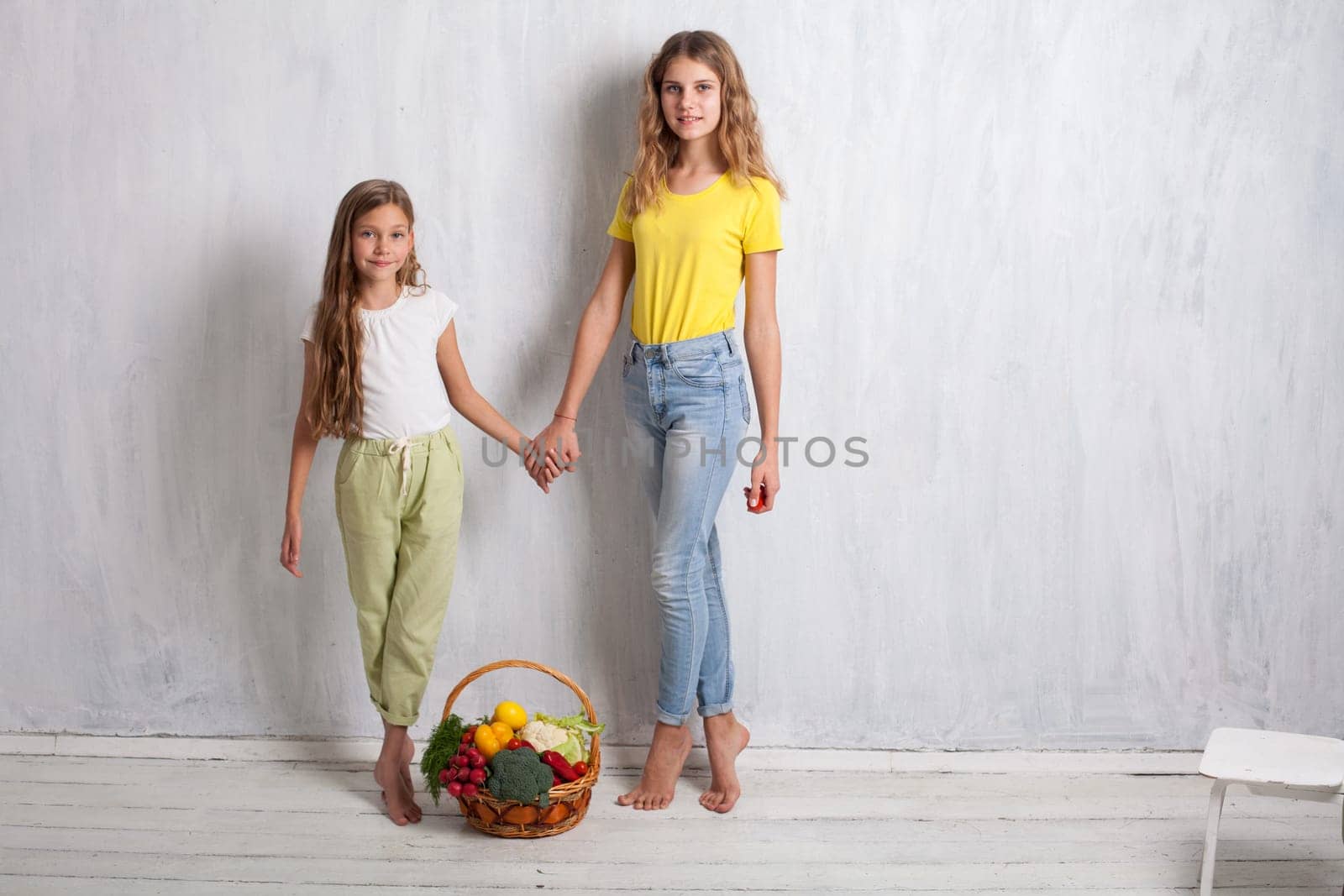 two girls holding a basket of ripe vegetables radish pepper by Simakov