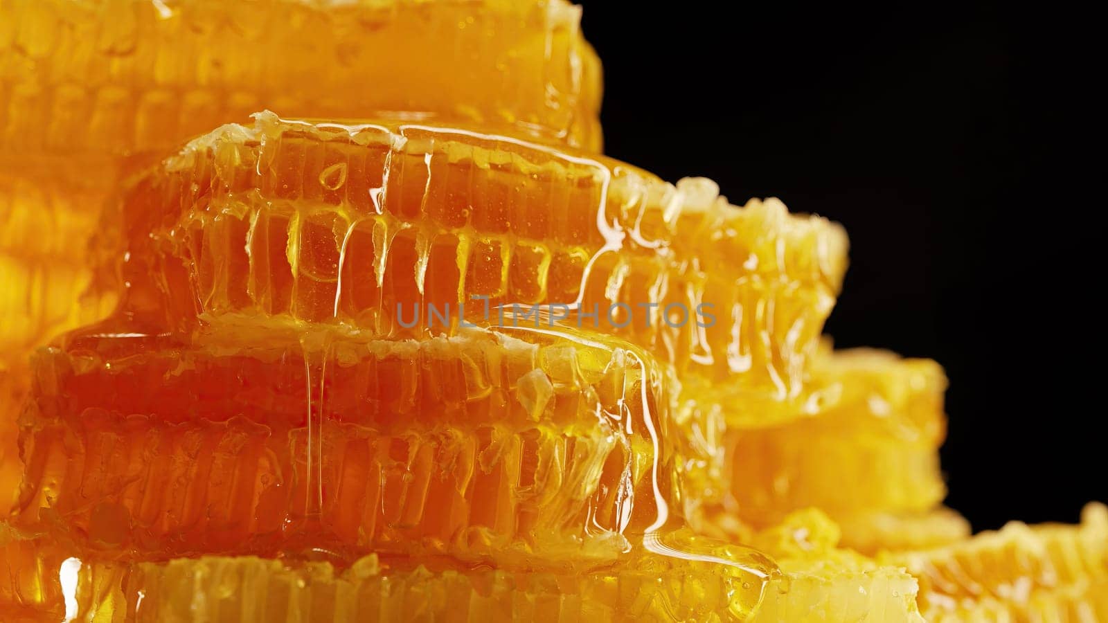 Raw honeycombs with pouring pure golden honey elixir. Amazing tasty flow. Macro texture, structure of flower nectar. Sweet visuals, stunning details. High quality