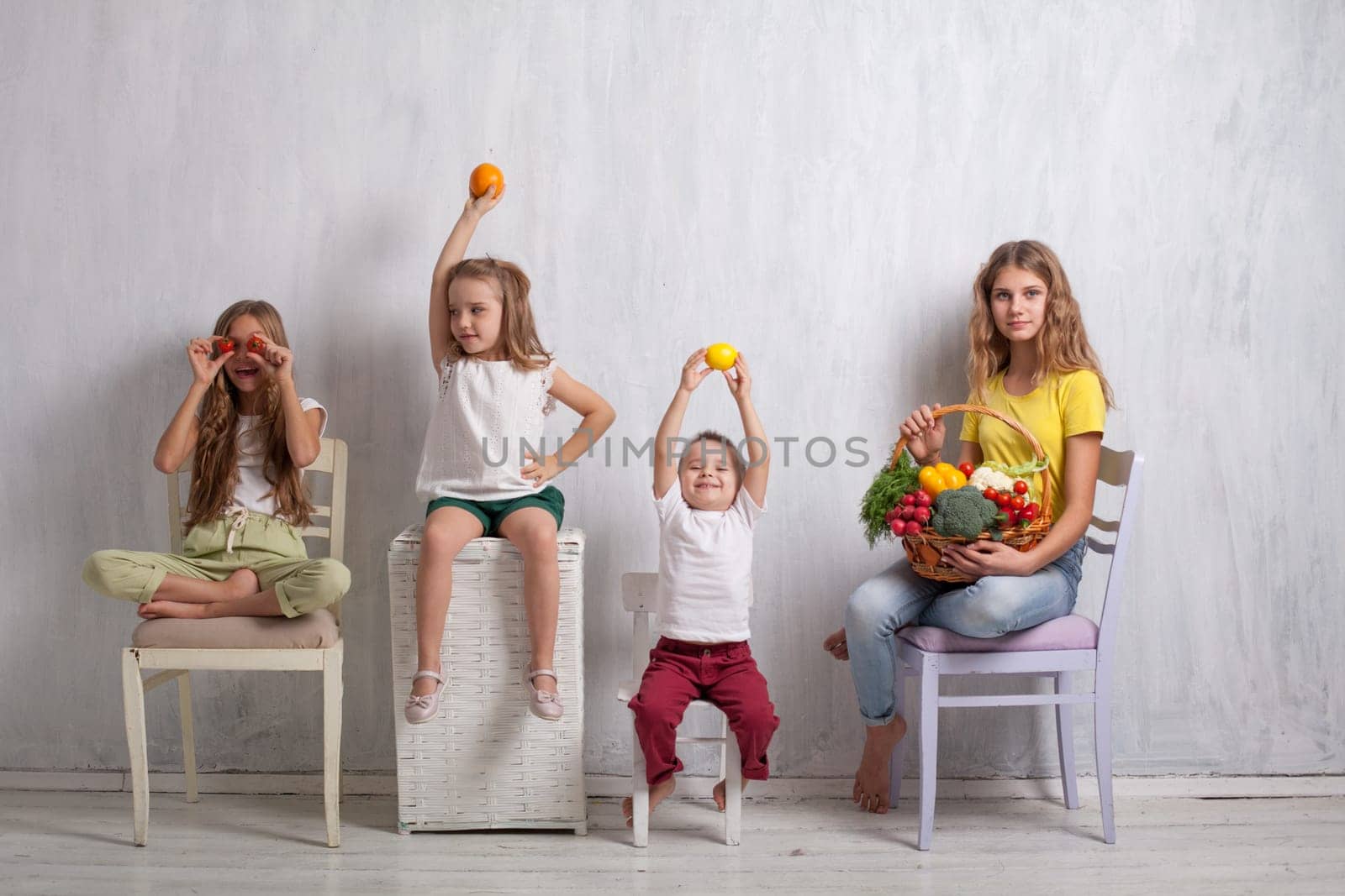kids boy and three girls with a basket of ripe vegetables and fruits
