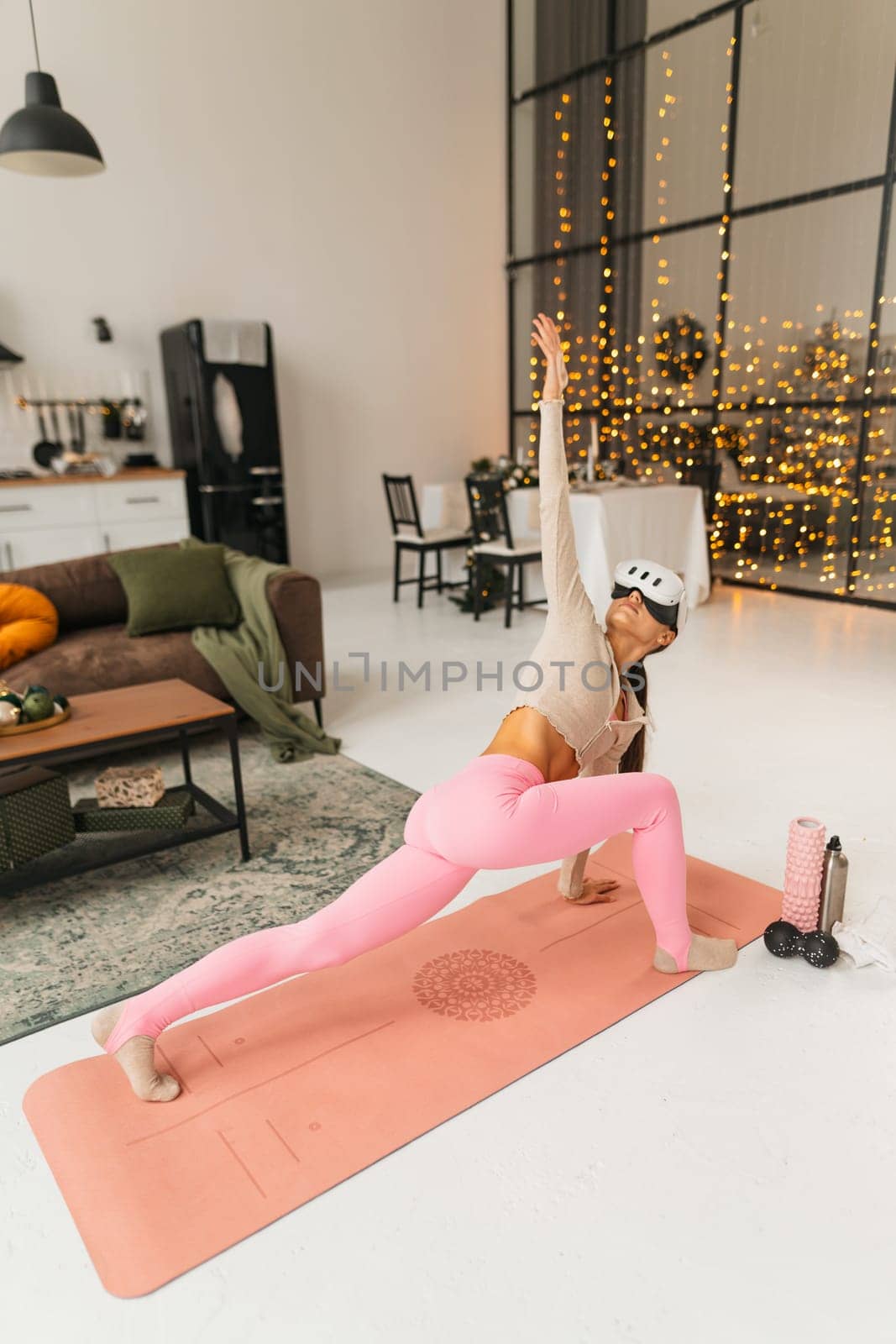 Doing sports exercises dressed in pink athletic attire and using a virtual reality headset with a Christmas tree in the background. by teksomolika