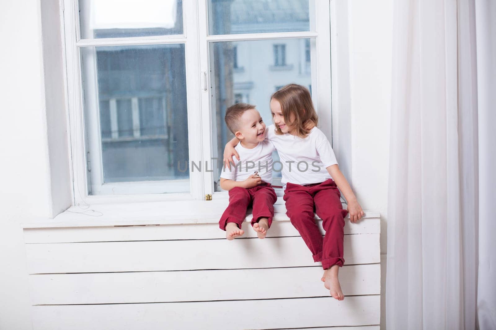 little boy and girl sitting by the window without parents