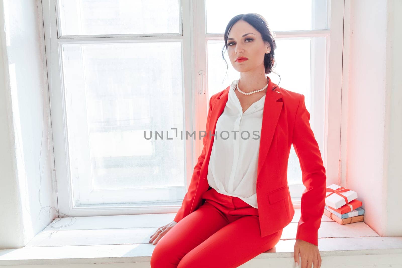 business woman brunette in a red business suit with a gift
