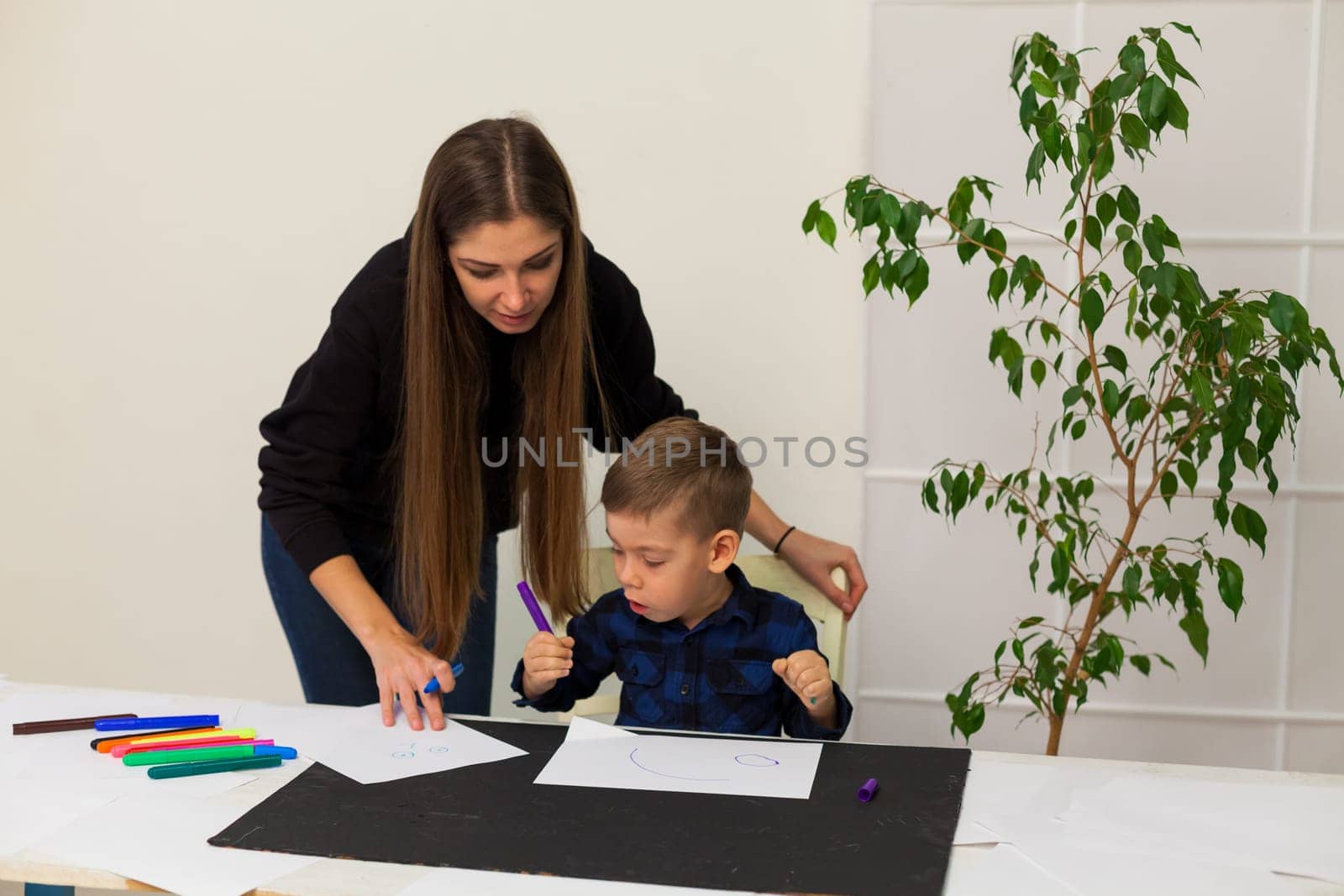 Woman teacher teaches boy to draw