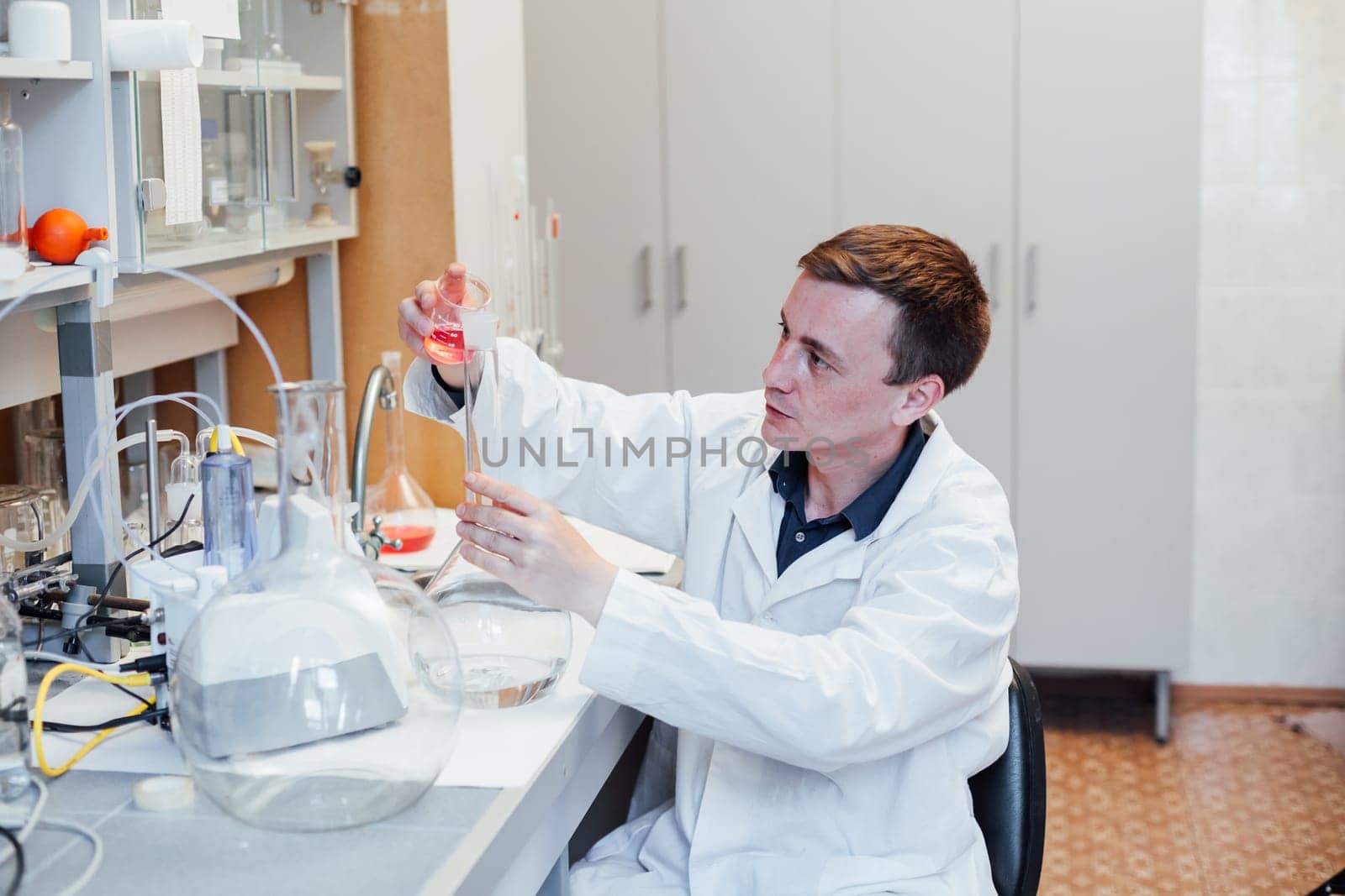 scientist conducts chemical experiments with liquids in the medical laboratory by Simakov