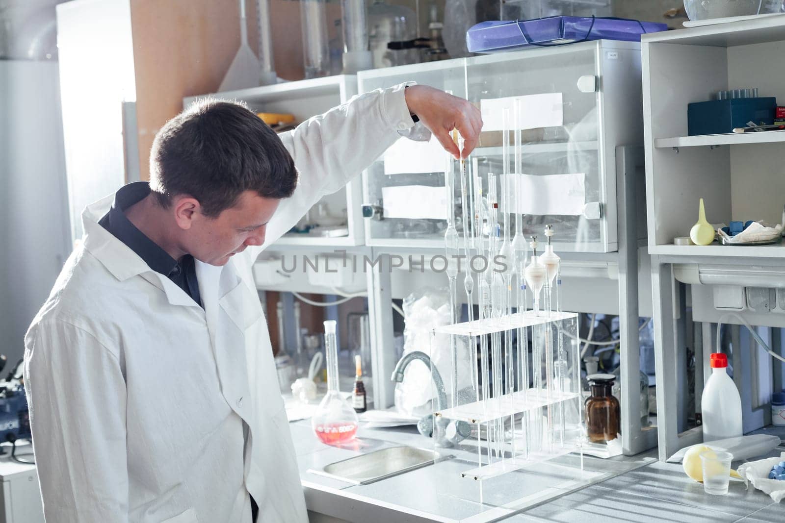 scientist conducts chemical experiments with liquids in the medical laboratory by Simakov