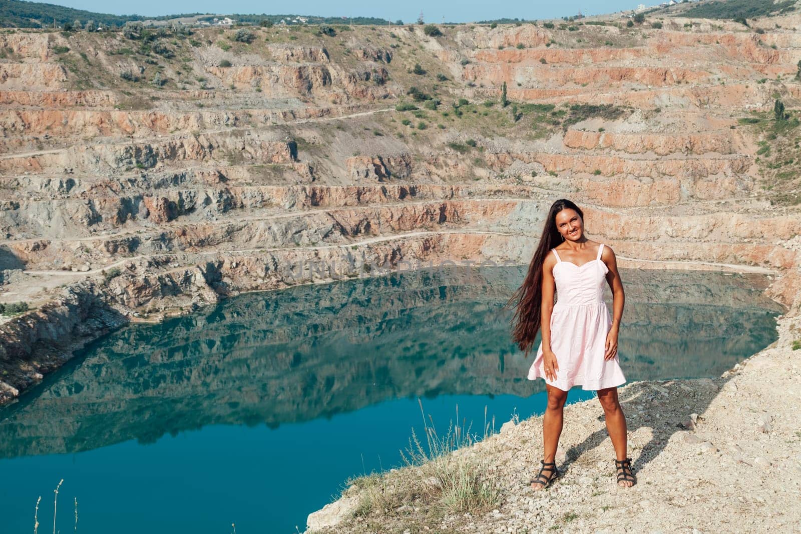 woman with long hair looks at the landscape from cliff trip