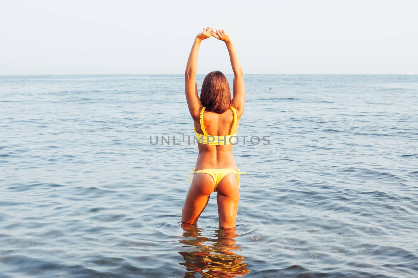 woman with long hair in yellow swimsuit on sea beach walk