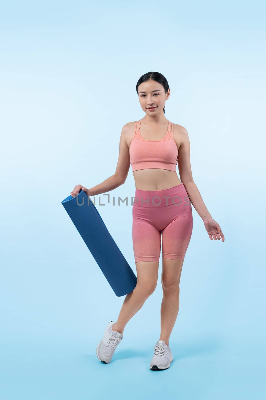 Young attractive asian woman portrait in sportswear with exercising mat. Healthy exercise and workout routine lifestyle concept. Studio shot isolated background. Vigorous