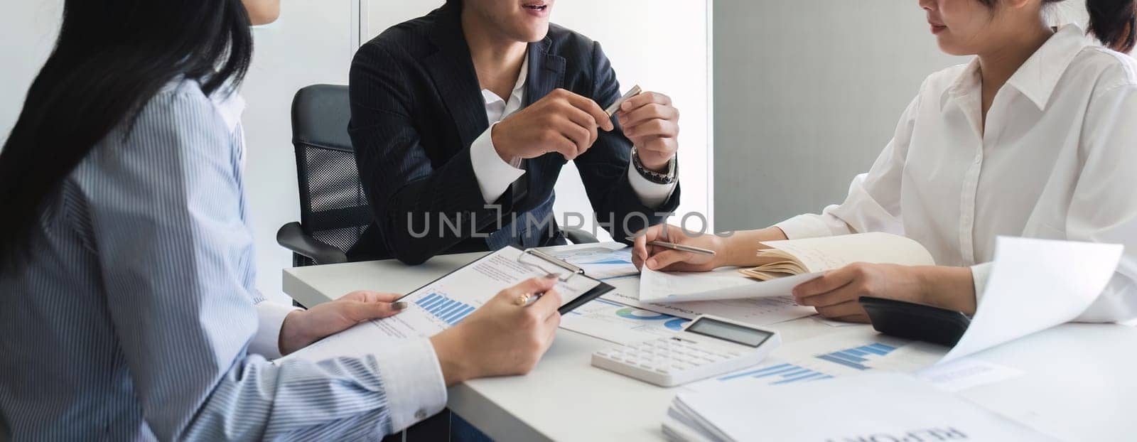 A professional business team is meeting to discuss company management practices in a modern conference room. close up view by wichayada