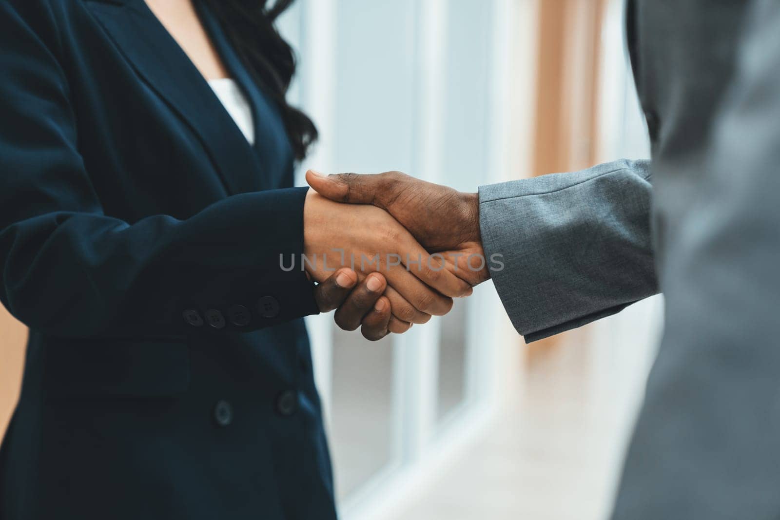 Closeup of business hands shaking between businesswoman and professional male leader at modern office corridor. Represented unity, corporate, collaborate, teamwork cooperation, joining. Ornamented.