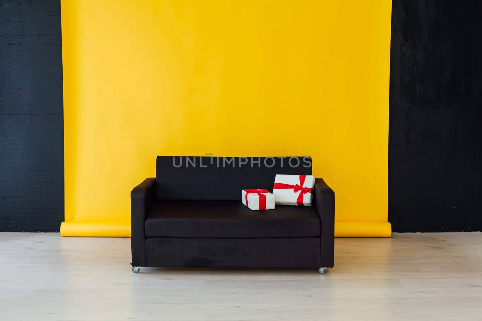 black office sofa with red gifts in the interior of the room with a yellow background