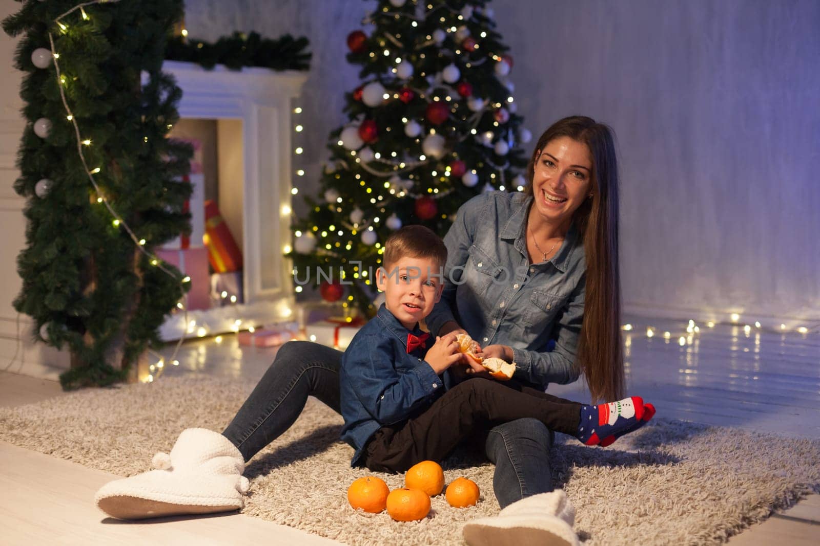 Mom and son on New Year's Eve at Christmas tree gifts lights