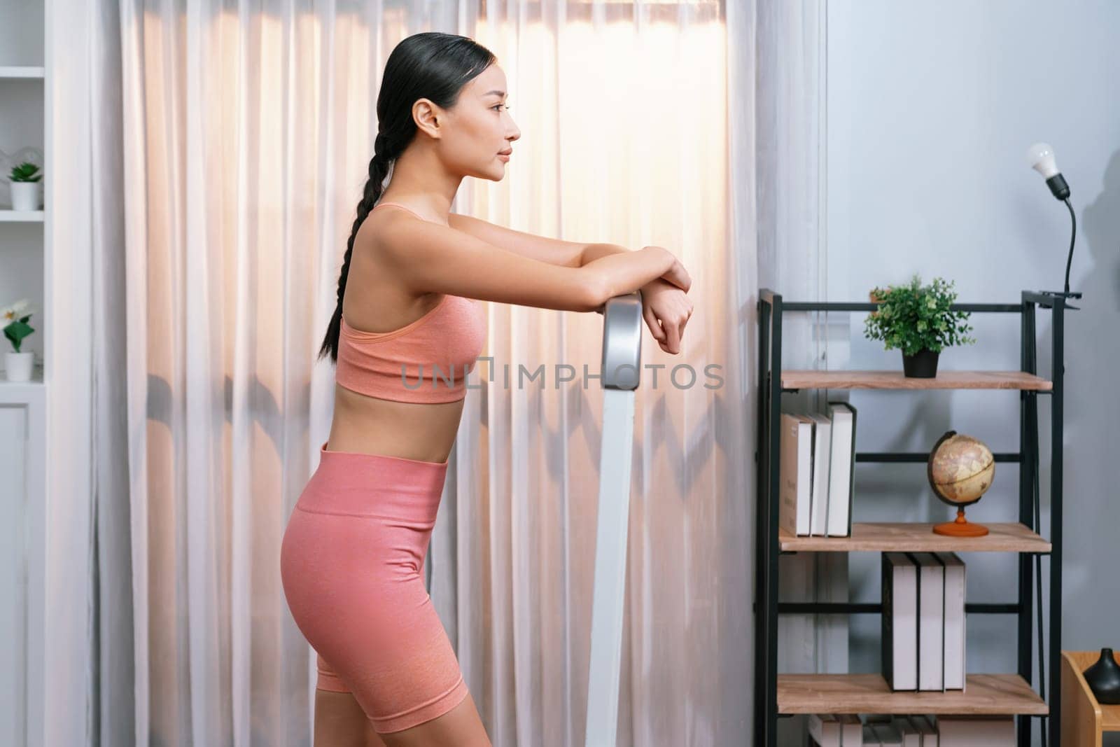 Full length side view of energetic and strong athletic asian woman running running machine at home. Pursuit of fit physique and commitment to healthy lifestyle with home workout and training. Vigorous