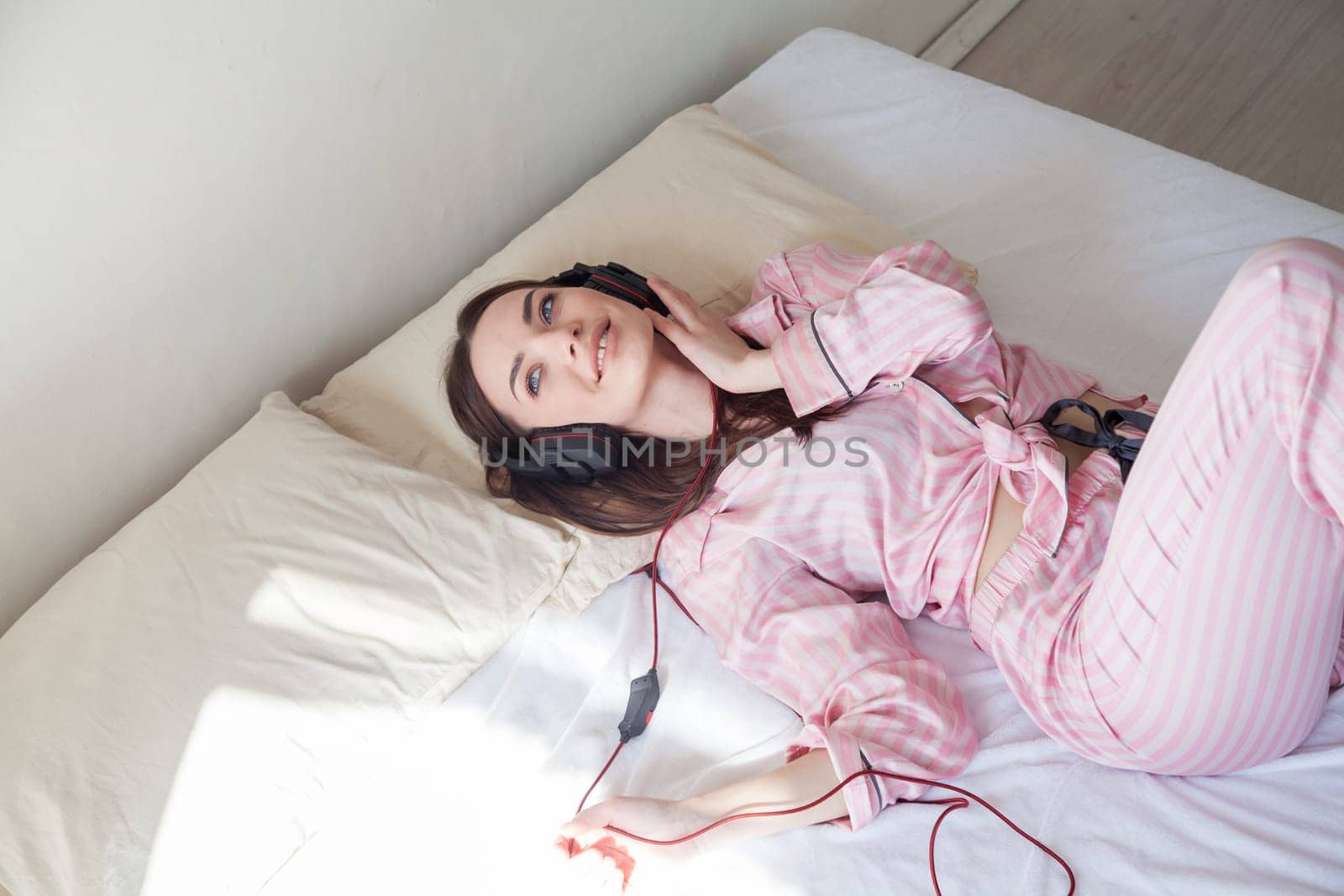 woman listens to music with headphones in the bedroom