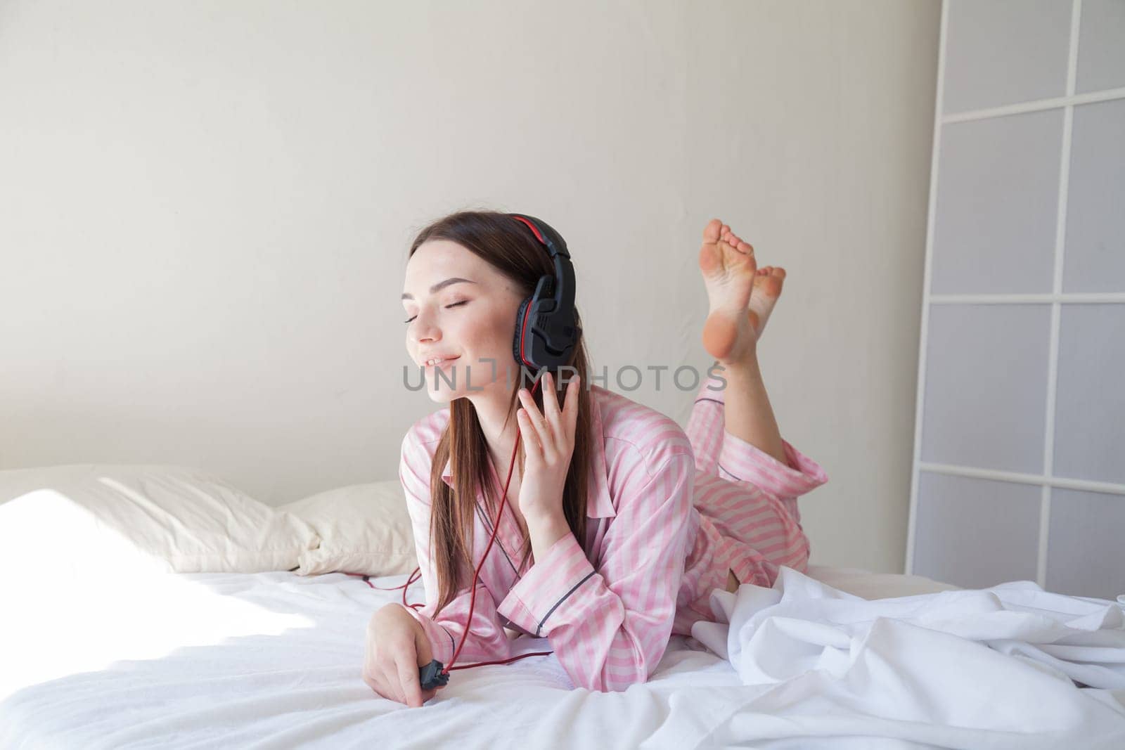 woman listens to music with headphones in the bedroom