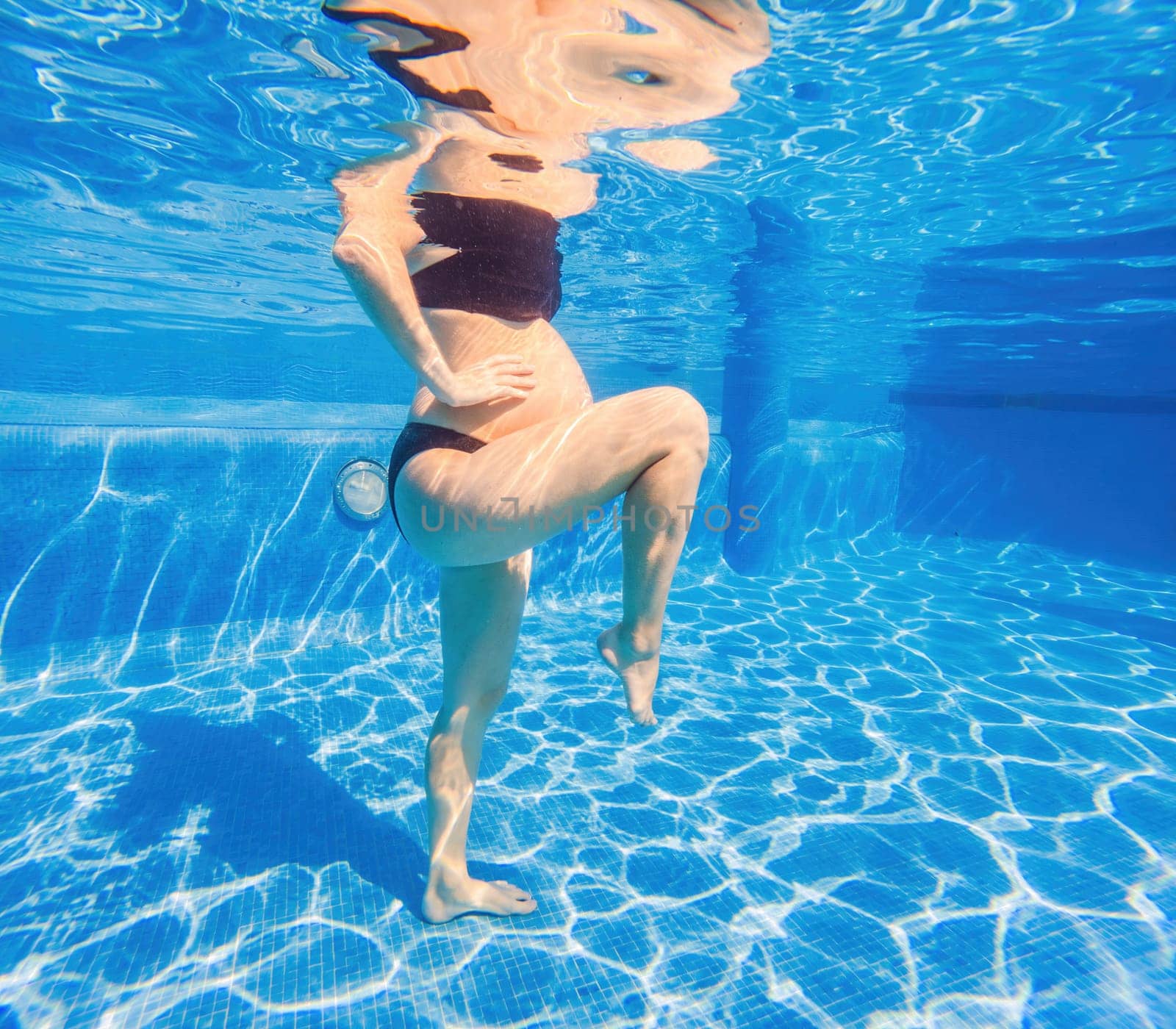 Embracing aquatic fitness, a pregnant woman demonstrates strength and serenity in underwater aerobics, creating a serene and empowering image in the pool by galitskaya