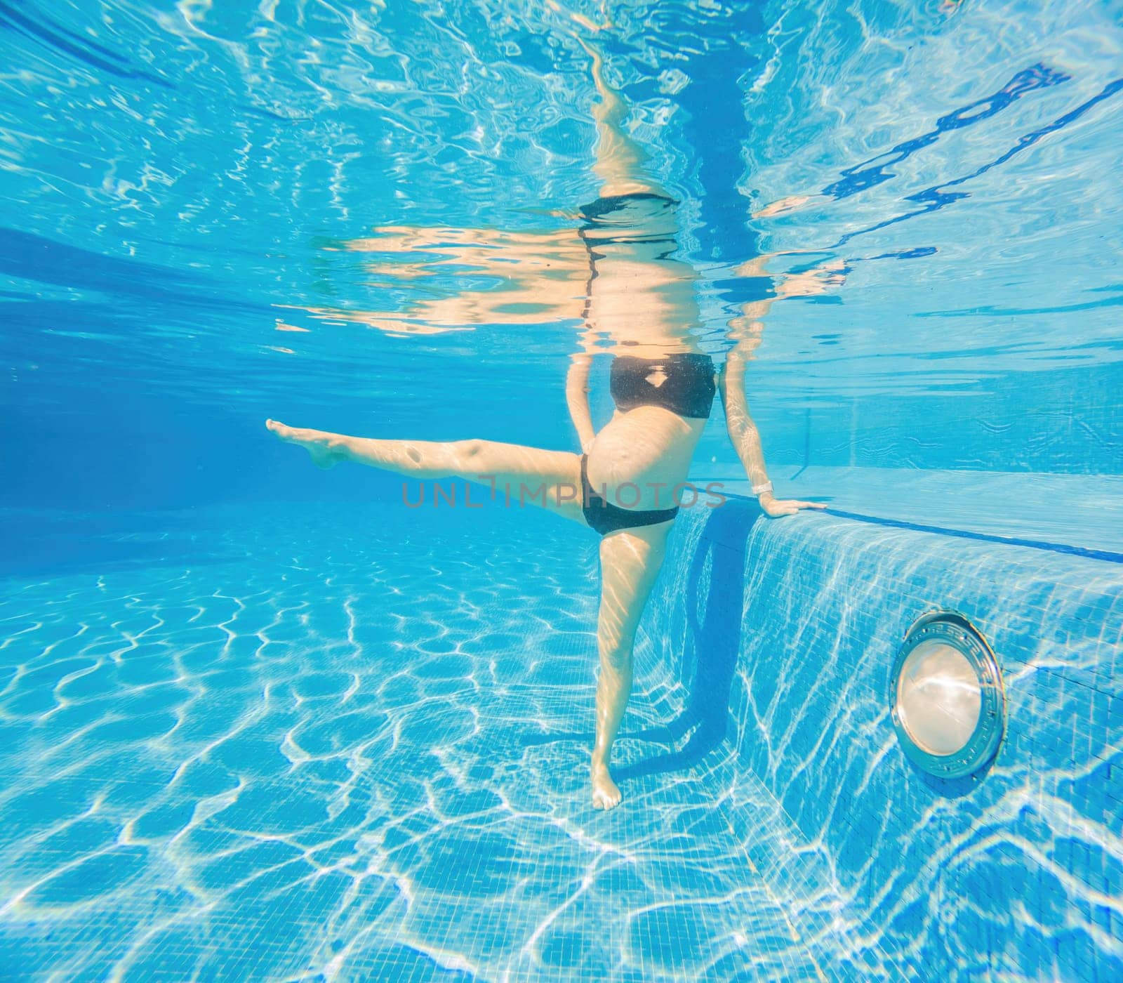 Embracing aquatic fitness, a pregnant woman demonstrates strength and serenity in underwater aerobics, creating a serene and empowering image in the pool by galitskaya