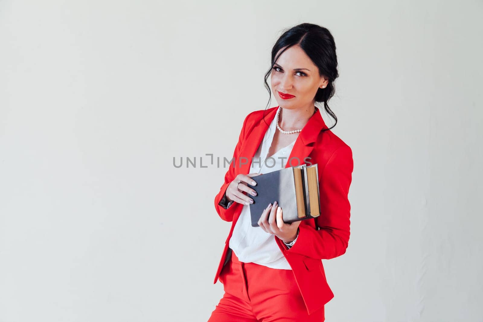 portrait of a beautiful woman with books in a red business suit in the office by Simakov