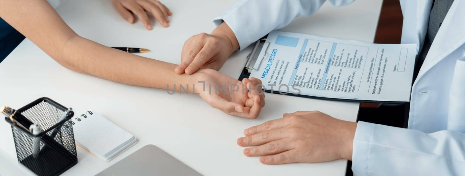 Patient attend doctor's appointment at clinic or hospital office. Doctor discusses medical treatment option, examining and diagnosis symptoms while checking the patient's pulse. Panorama Rigid