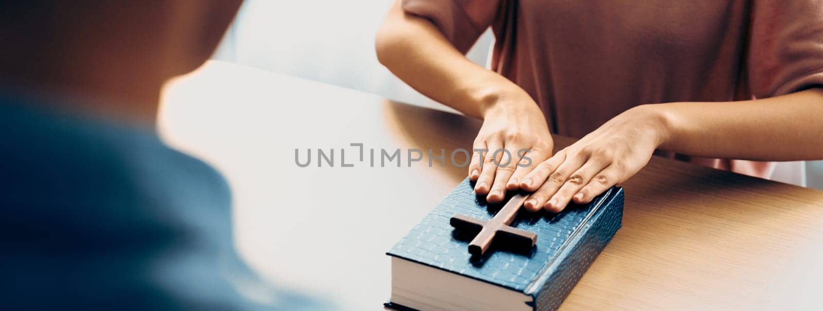 Close-up women prayer deliver holy bible book and holy cross to male believer. Spreading religion symbol. Concept of hope, religion, christianity and god blessing. Warm background. Burgeoning.