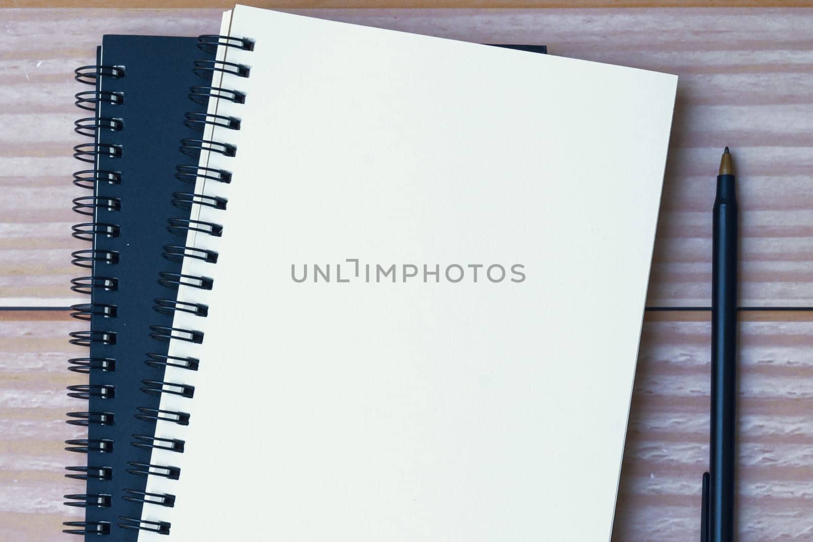 Directly above view of a pen with notepad on wooden desk. Flat lay. Copy space.