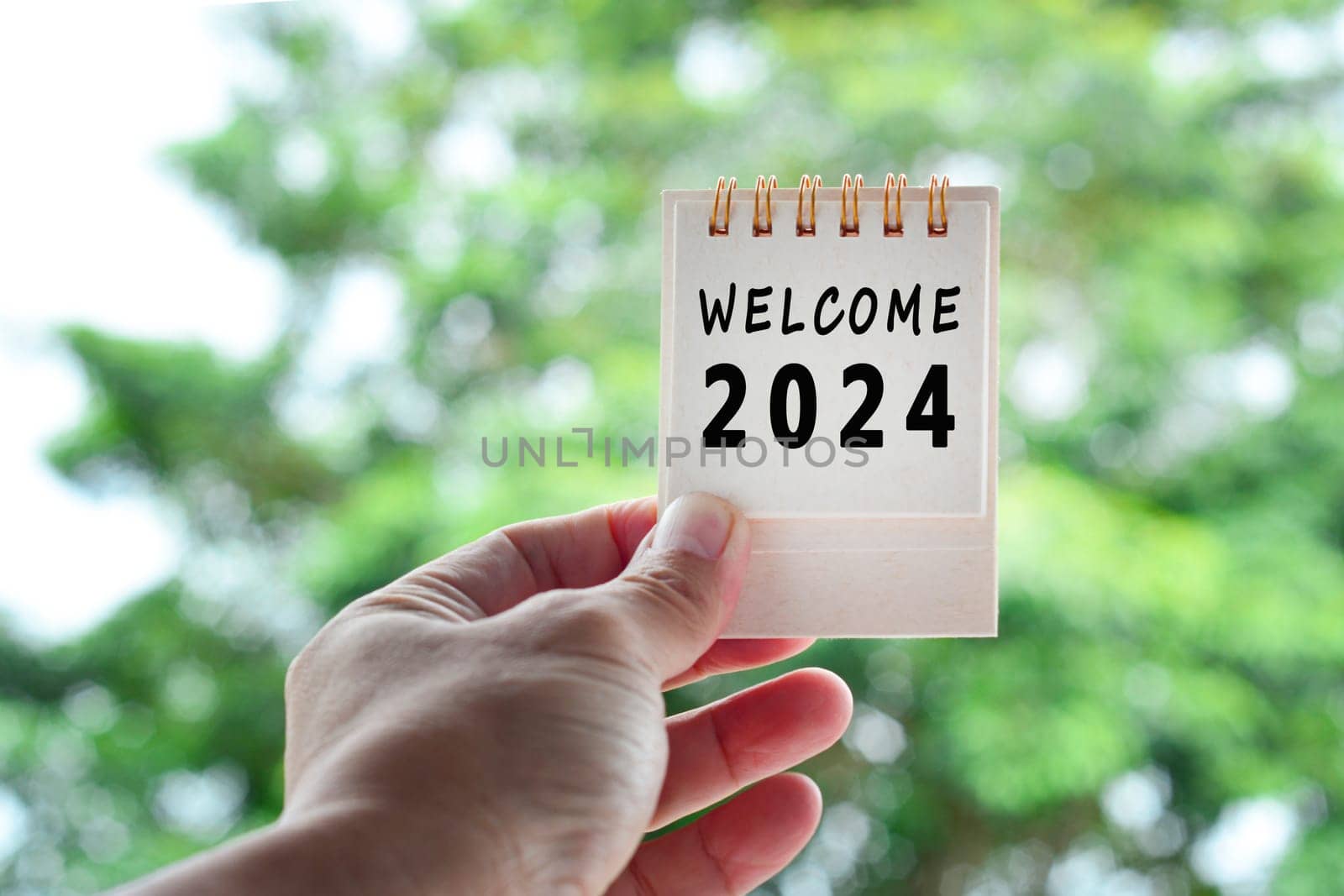 Hands Holding Calendar 2024 with blurred green background. Happy New Year 2024 concept.