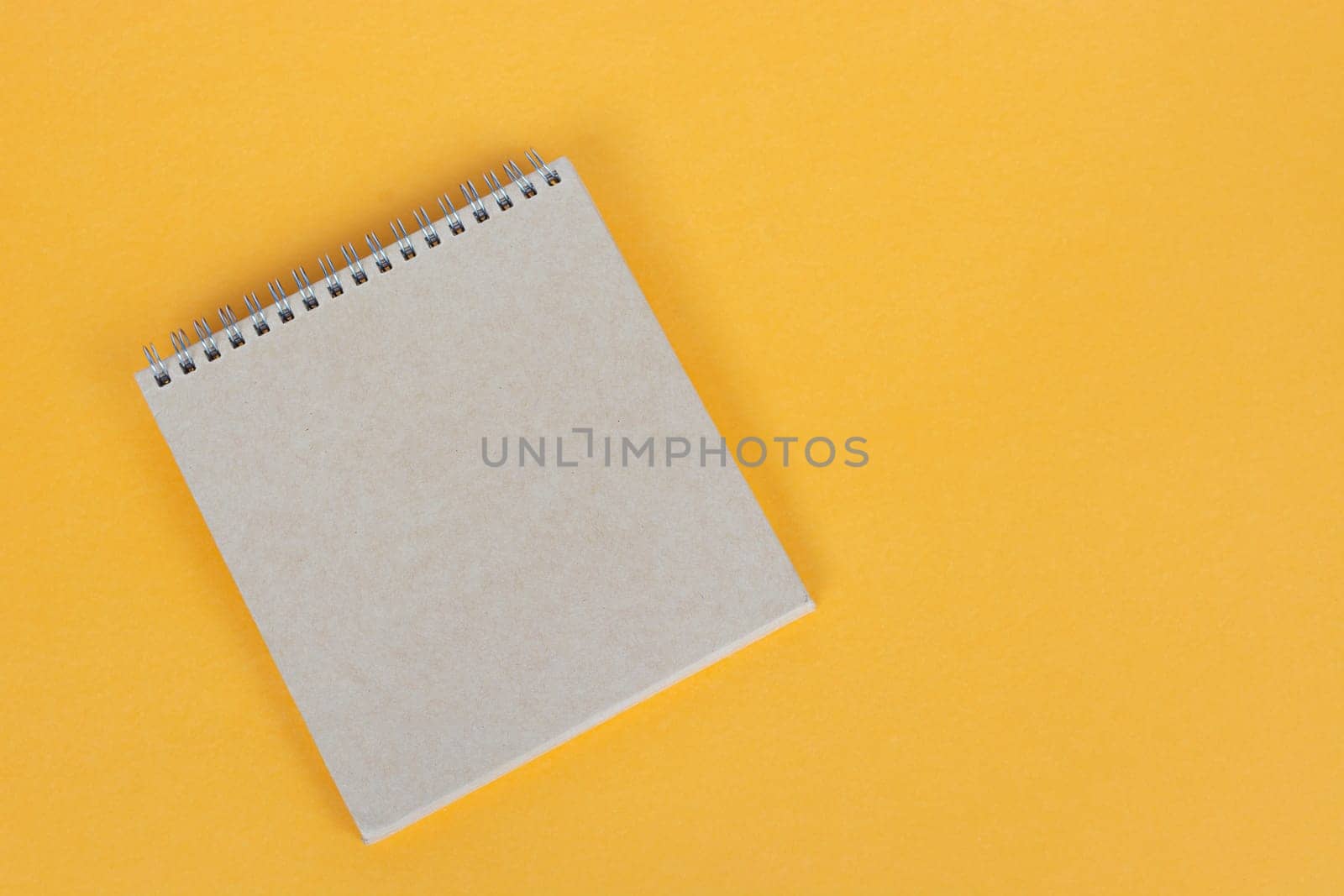 Top view of brown notepad on yellow background. Copy space. Flat lay.