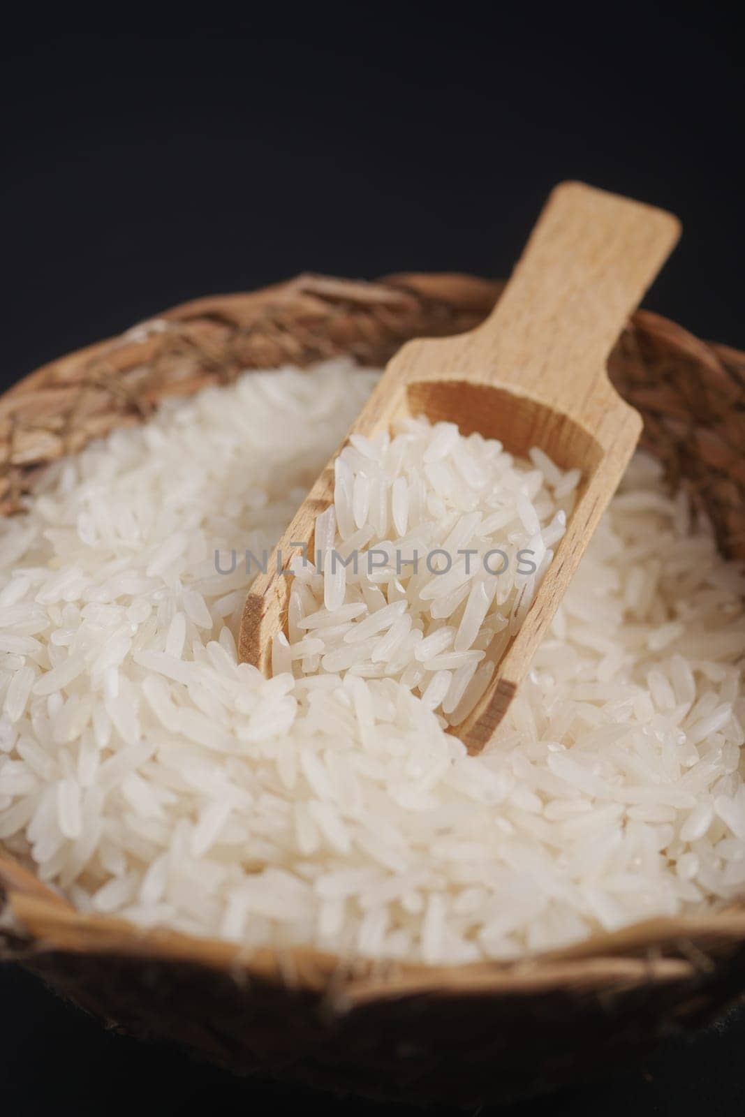 Raw white rice on a wooden spoon .