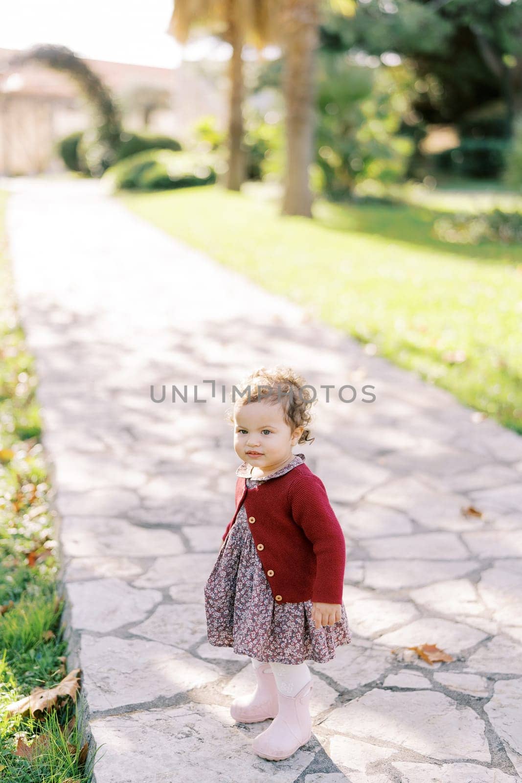 Little smiling girl stands on a paved path by Nadtochiy