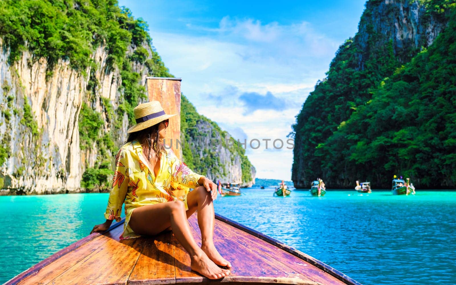 Asian women in front of a longtail boat at Kho Phi Phi Thailand at Pileh Lagoon with turqouse water by fokkebok