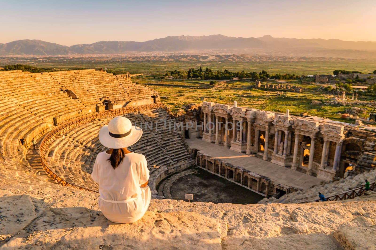 Hierapolis ancient city Pamukkale Turkey, a young woman with a hat watching the sunset by the ruins Unesco Heritage. Asian women watching the sunset at the old Amphitheater in Turkey during vacation trip