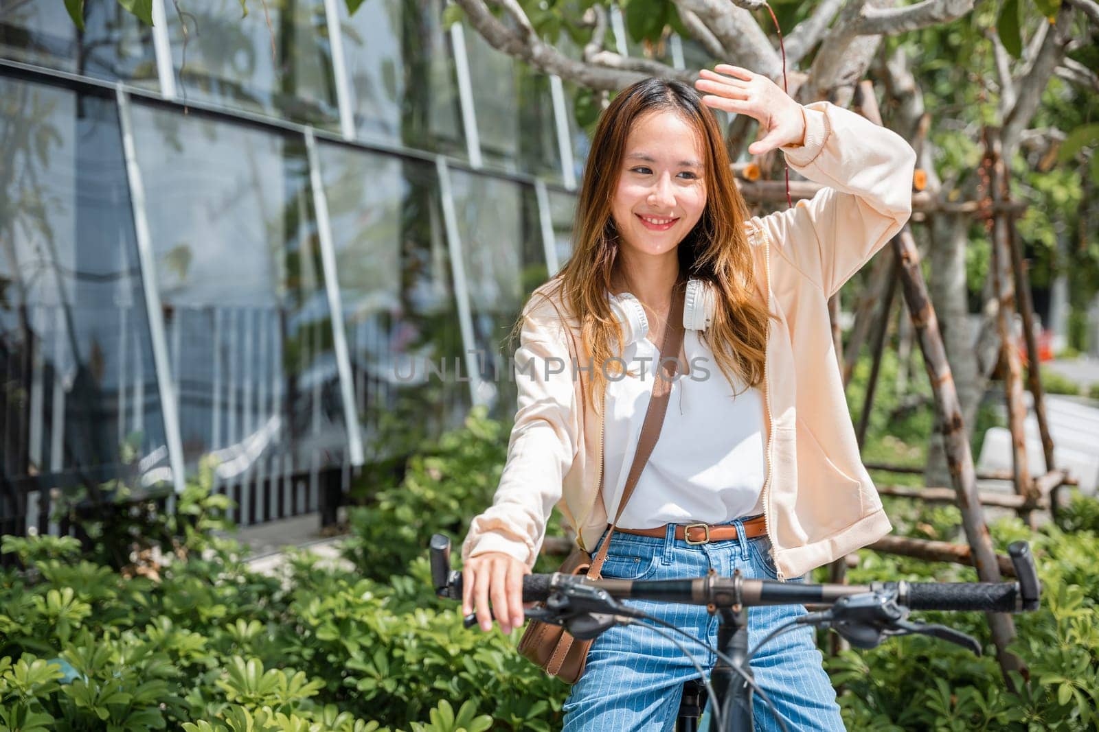 Amidst the city a cheerful young woman shields from the hot sun on her bicycle capturing the beauty of outdoor fun and fashion. This season is all about happiness and nature.