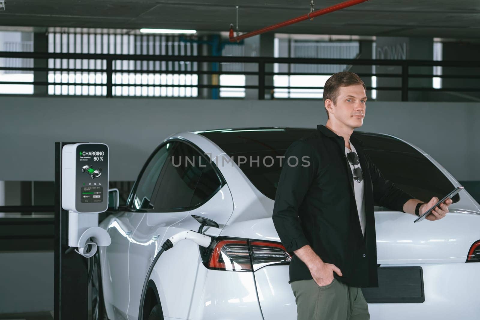 Young man travel with EV electric car to shopping center parking lot innards by biancoblue