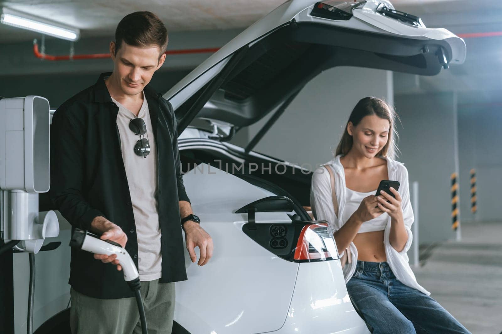 Young couple travel with EV electric car to shopping center parking lot innards by biancoblue