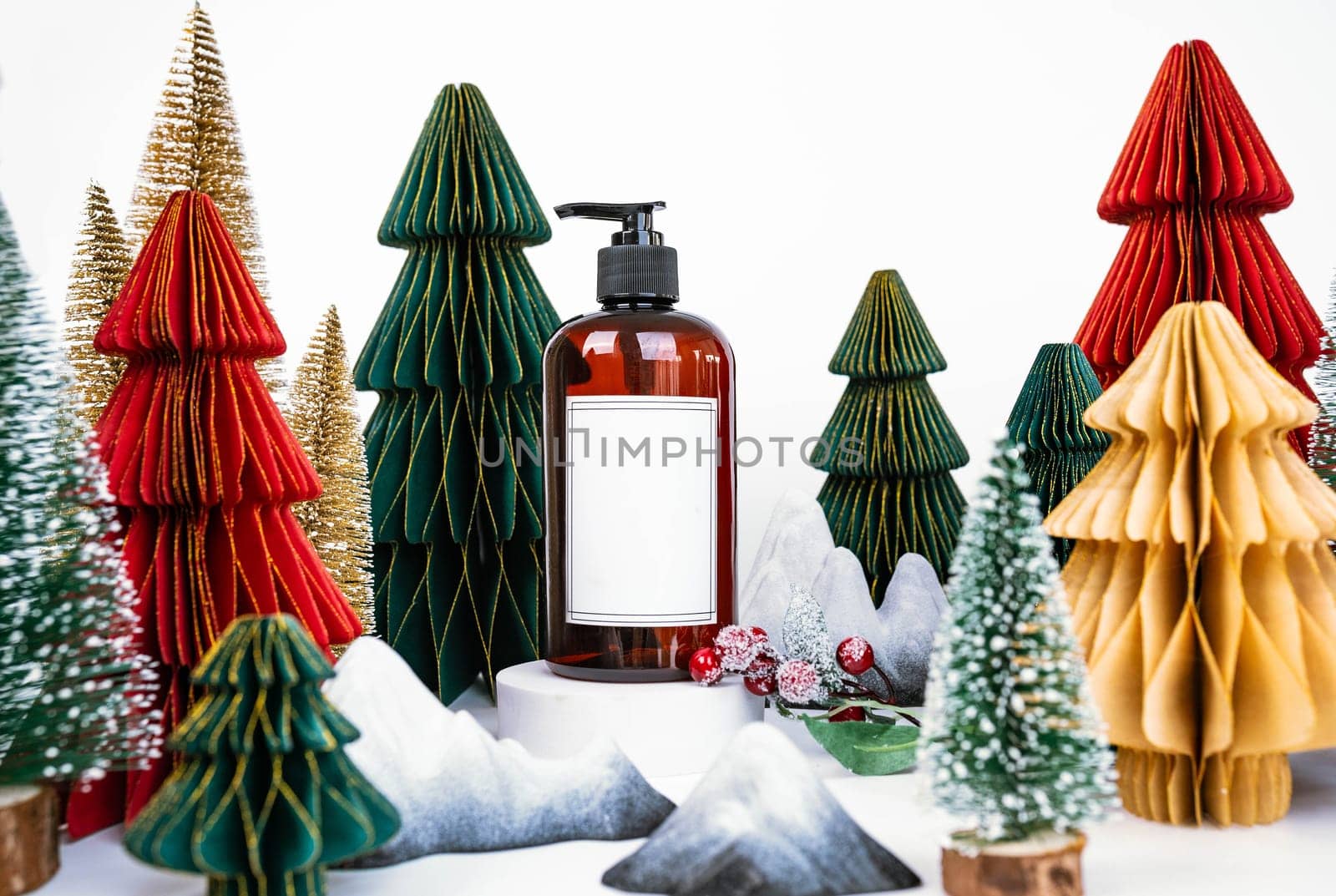 Bottle with dispenser and white sticker on Christmas background with colored Christmas trees. New Year's Eve Advertising Concept. High quality photo