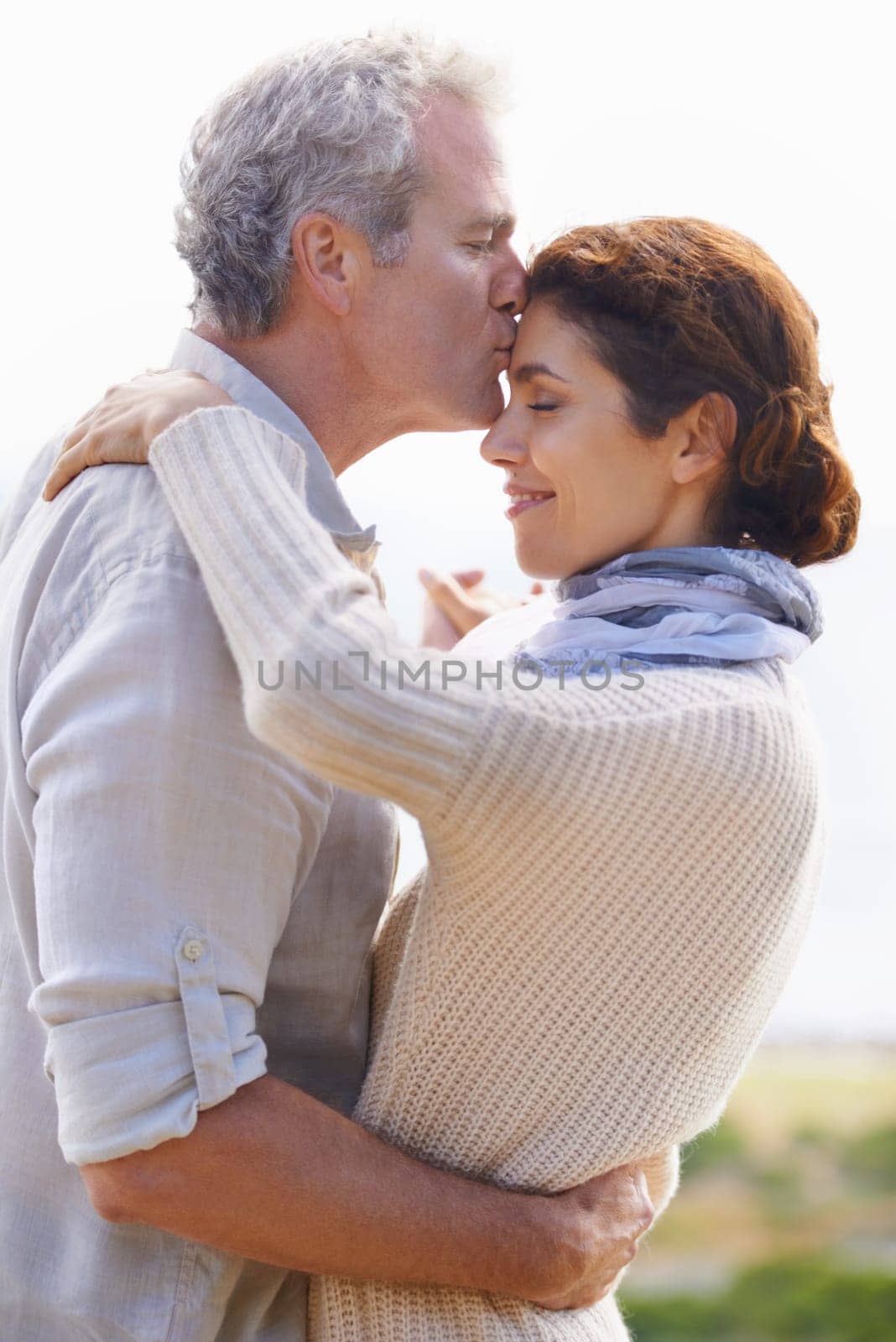 Couple, kiss and hug in outdoors, travel and bonding or love, affection and security in relationship. Mature people, happy and relaxing on vacation, holiday and adventure or getaway, embrace or care.