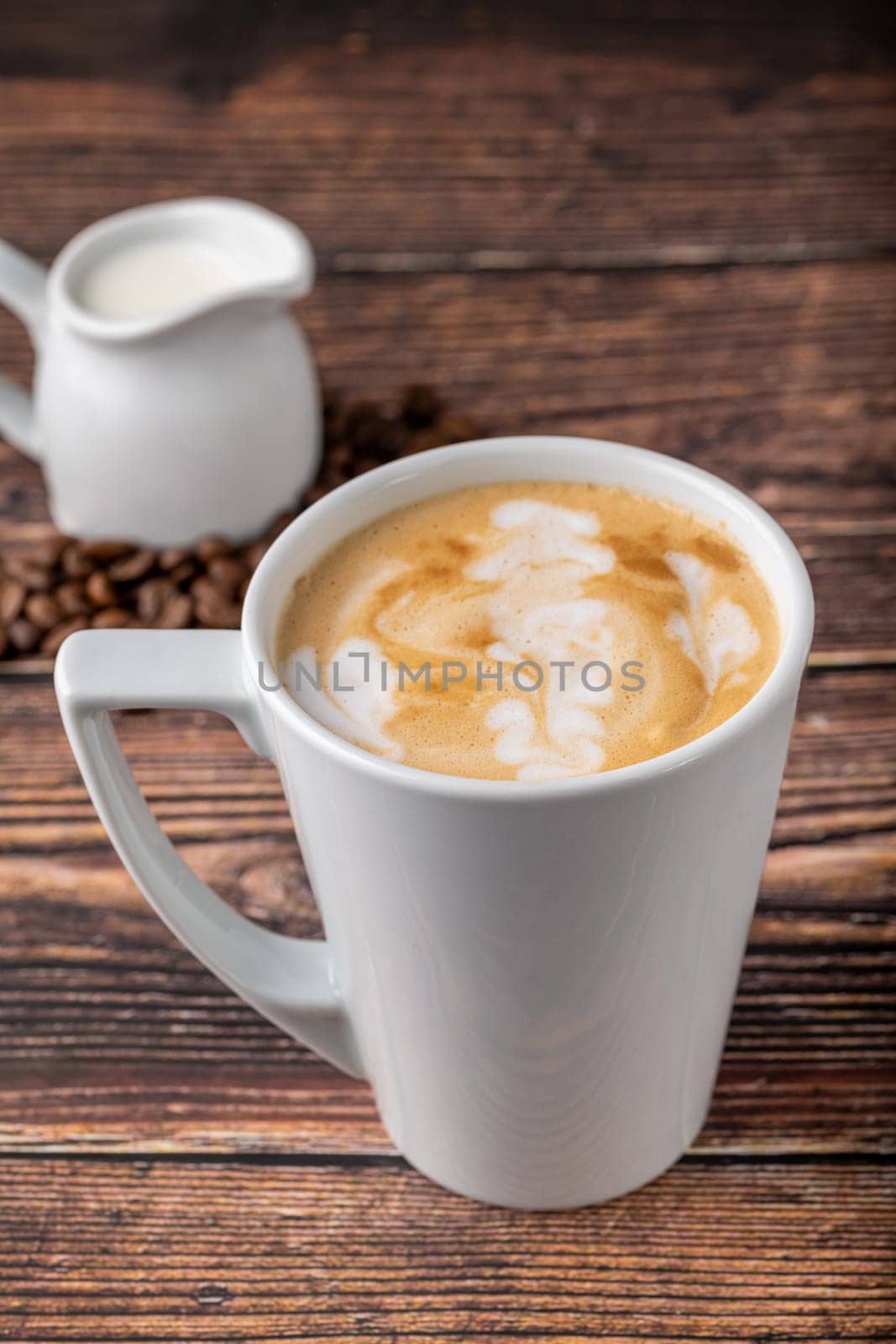 Relaxing latte coffee in white porcelain cup on wooden table by Sonat