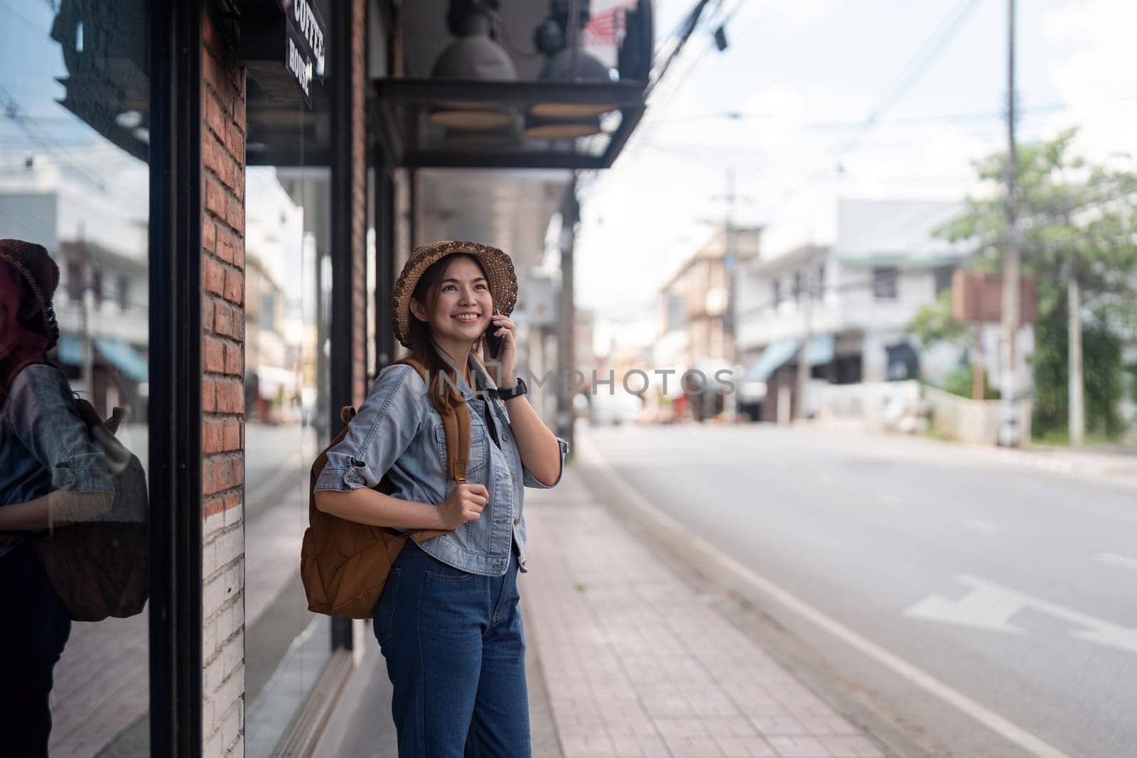 Happy young Asian tourist woman using smartphone on street with market background, Female traveller enjoy shopping market during holidays.