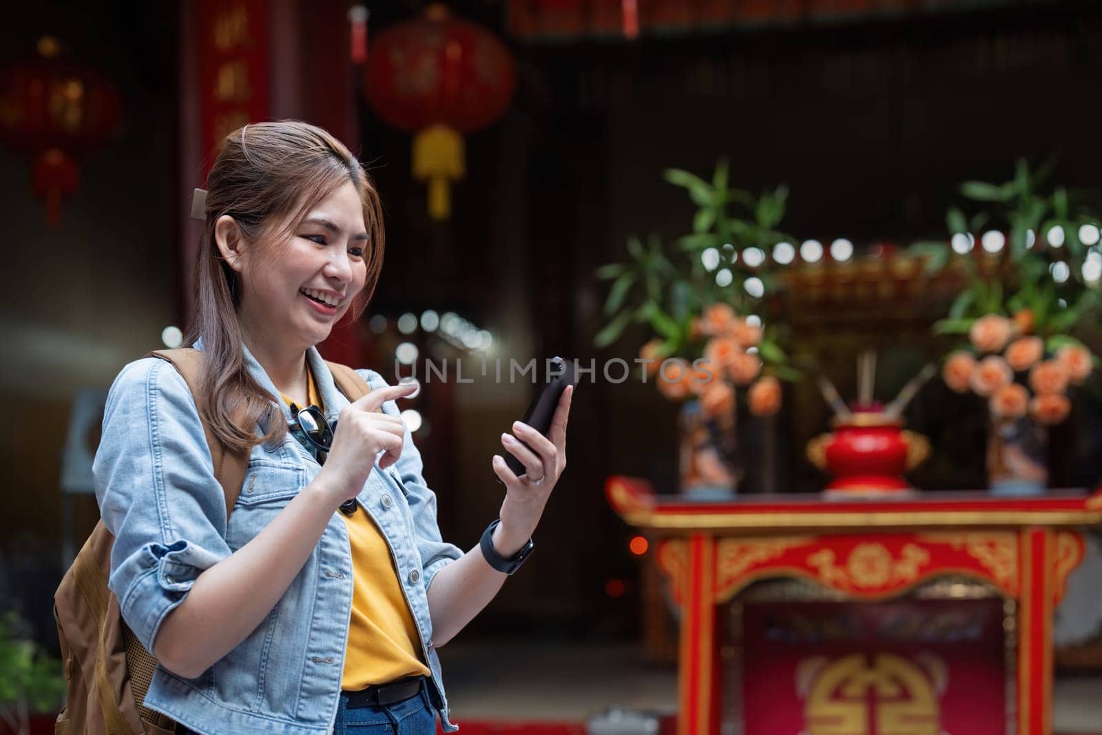 Happy young Asian tourist woman using smartphone on street with market background, Female traveller enjoy shopping market during holidays.