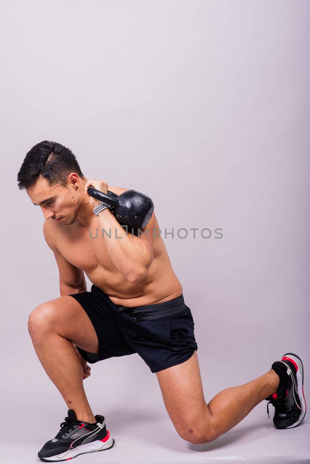 Handsome muscular man holding a kettle bell with copy space. Hispanic male athlete